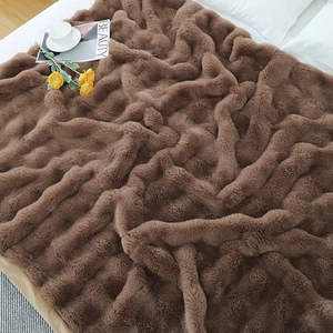 Detailed texture of thick dark brown faux rabbit fur blanket on a white bed sheet