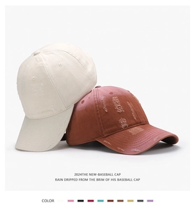 Detail view of washed distressed cotton baseball caps in beige and brick red colors