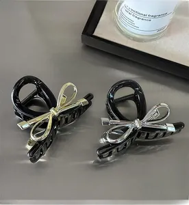 Detail of black shark clips with gold and silver metal bows on a modern display