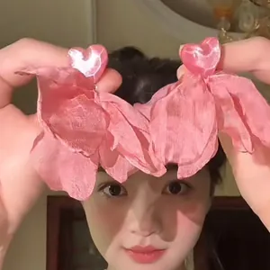 Detailed view of pink shell heart earrings with layered fabric petals on female model