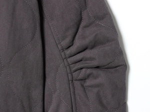 Macro view showing the quilted fabric texture and pleated seam detail on this bomber jacket