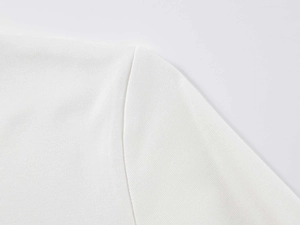 Vue macro détaillée montrant la texture en maille et la couture de l'épaule du t-shirt blanc