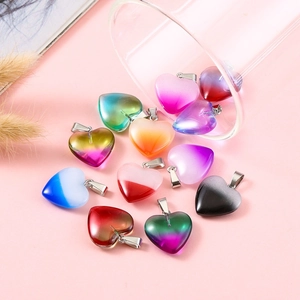 Colorful heart shaped stone pendants with metal clasp scattered on pink background