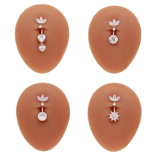 Détail de quatre piercings de nombril argentés avec zircons en cœur sur des modèles silicone