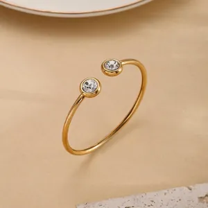 Minimalist evil eye gold bangle with two sparkling crystals on a textured stone display