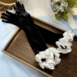 Detail of vintage black long gloves featuring elegant white ruffled puff sleeve cuffs