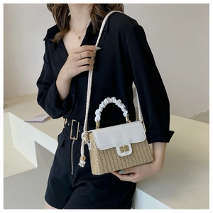 Detail of straw woven bucket bag with white leather flap and gold buckle closure
