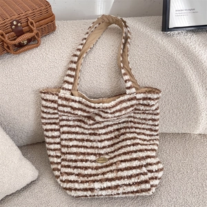 Close-up of brown and white striped plush tote bag with a golden brand metal logo