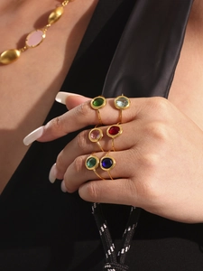Detailansicht vergoldeter Ringe mit bunten runden Glassteinen und offenem Design