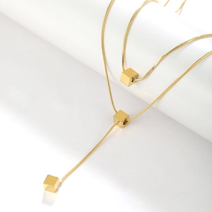 Detail of gold snake chain necklace featuring three minimalist metal cube pendants
