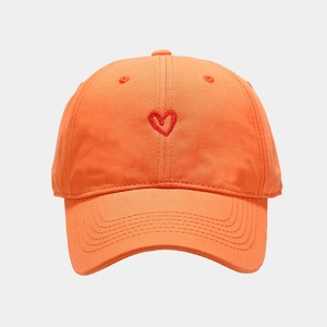 Close-up of a bright orange cotton baseball cap with red heart embroidery on the front