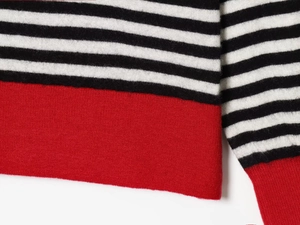 Close-up of black and white striped knit fabric with a bold red hem and ribbed cuffs