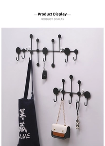 Wall-mounted black iron coat rack with geometric circular hooks holding bags and keys