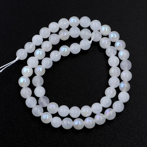 Macro shot of white moonstone loose beads with blue sheen on a black textured surface