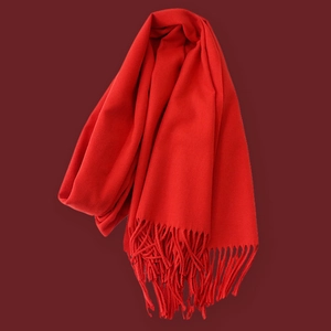 Detail of red winter knit scarf with fringe edge, soft cashmere texture close-up