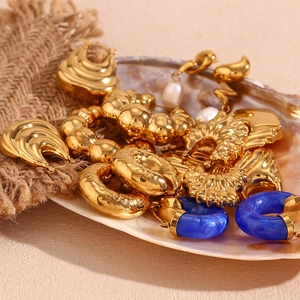Detail of 18K gold geometric earrings with blue marble and pearls in shell tray
