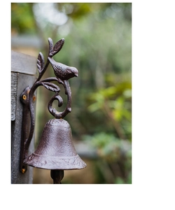 Detailed view of vintage cast iron doorbell featuring a bird on a rustic branch