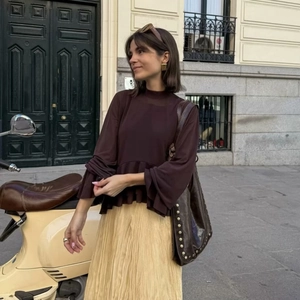 Elegant yellow pleated maxi skirt paired with brown top in a stylish urban street setting