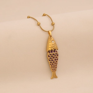 Macro detail of golden fish pendant with purple enamel scales and crystal eye on snake chain