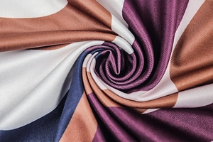 Detail of silky satin fabric with geometric abstract print in purple and brown tones