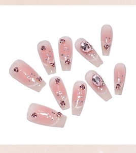Close-up of pink gradient press-on nails with sparkling rhinestones and silver glitters
