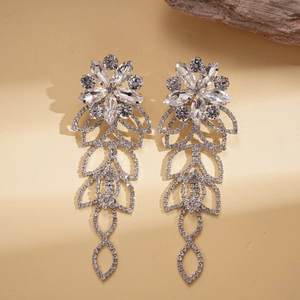 Luxurious silver flower and hollow leaf drop earrings with white crystals on warm background