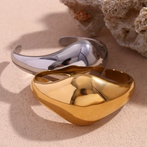Macro detail of high-polished gold and silver teardrop rings on natural stone