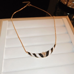 Detail der Goldkette mit schwarz-weiß gestreiftem Halbmond-Anhänger und klaren Strasssteinen