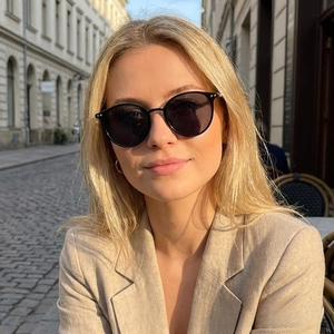 Retro black round frame sunglasses on a woman in an urban street fashion setting