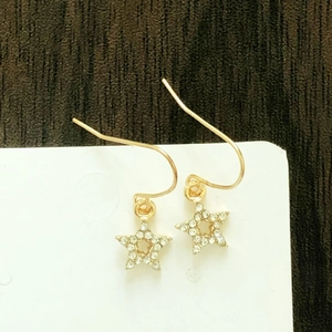Detail of star-shaped gold earrings featuring shimmering white zircon stones