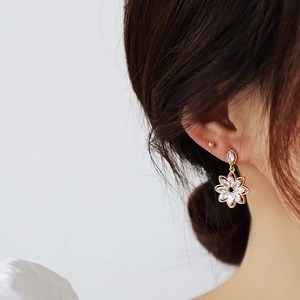 Detail of elegant gold flower drop earring with marquise cubic zirconia on female model