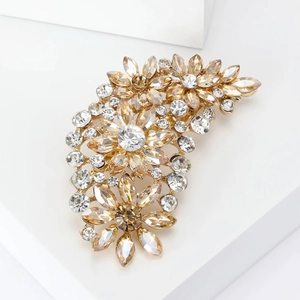 Detailed macro view of a vintage gold floral brooch with sparkling clear crystals