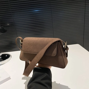 Close-up of a brown suede shoulder bag with a flap closure and wide strap