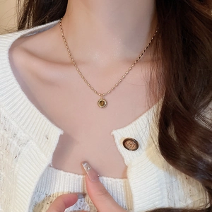 Detail of a vintage golden chain necklace with round brown tiger eye stone on a model