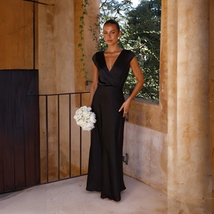 Detailed close-up of glossy black satin V-neck mermaid dress on a model in sunlight