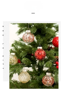 Detail of glittery red and gold patterned Christmas tree ornaments on green branches