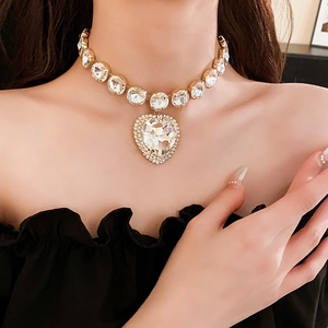 Close-up of sparkling heart pendant and gold collar necklace with rhinestones on model