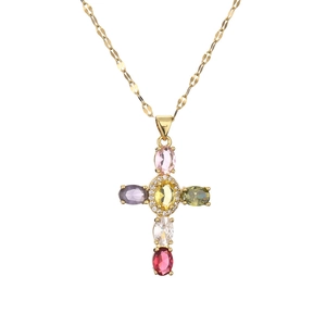 Cross necklace with multicolored zircons on a golden flat curb chain on white background