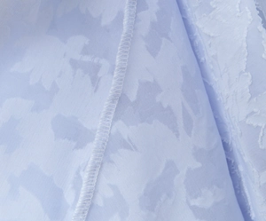 Detailed macro view of lilac jacquard fabric with leaf texture and fine edge stitching