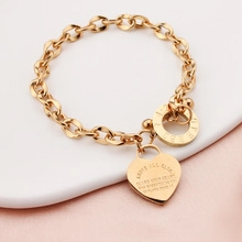 Macro view of gold heart pendant with inspirational engraving on thick link chain