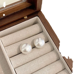Elegant round pearl stud earrings displayed in a luxury linen jewelry box for women