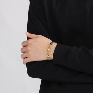 Detail of two-tone gold and silver Cuban link bracelet with anchor clasp on wrist