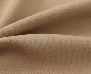 Gros plan sur un tissu kaki à grain fin montrant un tissage sergé doux et un beau drapé