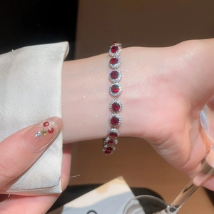 Gros plan d'un bracelet élégant avec pendentifs en zircon rouge sur fond de soie
