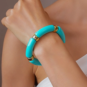 Dettaglio di perle acriliche turchesi e distanziatori in metallo dorato sul bracciale
