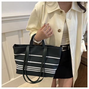Detail of striped canvas tote bag showing texture and drape on model's shoulder