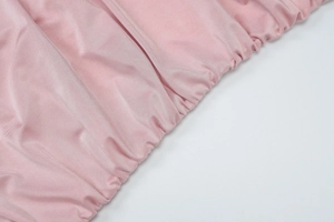 Dettaglio ravvicinato del tessuto in maglia rosa con texture elegante e pieghe elastiche