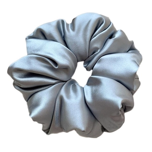 Close-up of light blue satin scrunchie showing smooth fabric texture and soft folds