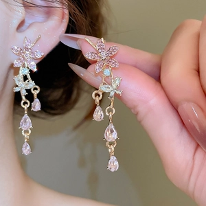 Close-up of long tassel earrings with pink floral motifs and shimmering crystal drops