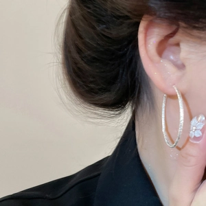 Close-up of model wearing large textured silver hoop earrings with a sparkling finish